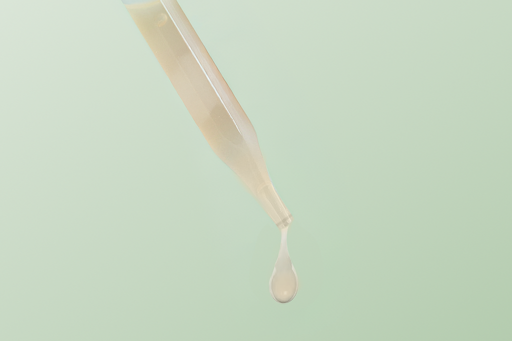 Dropper releasing a droplet of Sukina Apothecary's Magic Fruit Brightening Serum, showing its lightweight, silky texture designed to brighten, purify, and even skin tone.